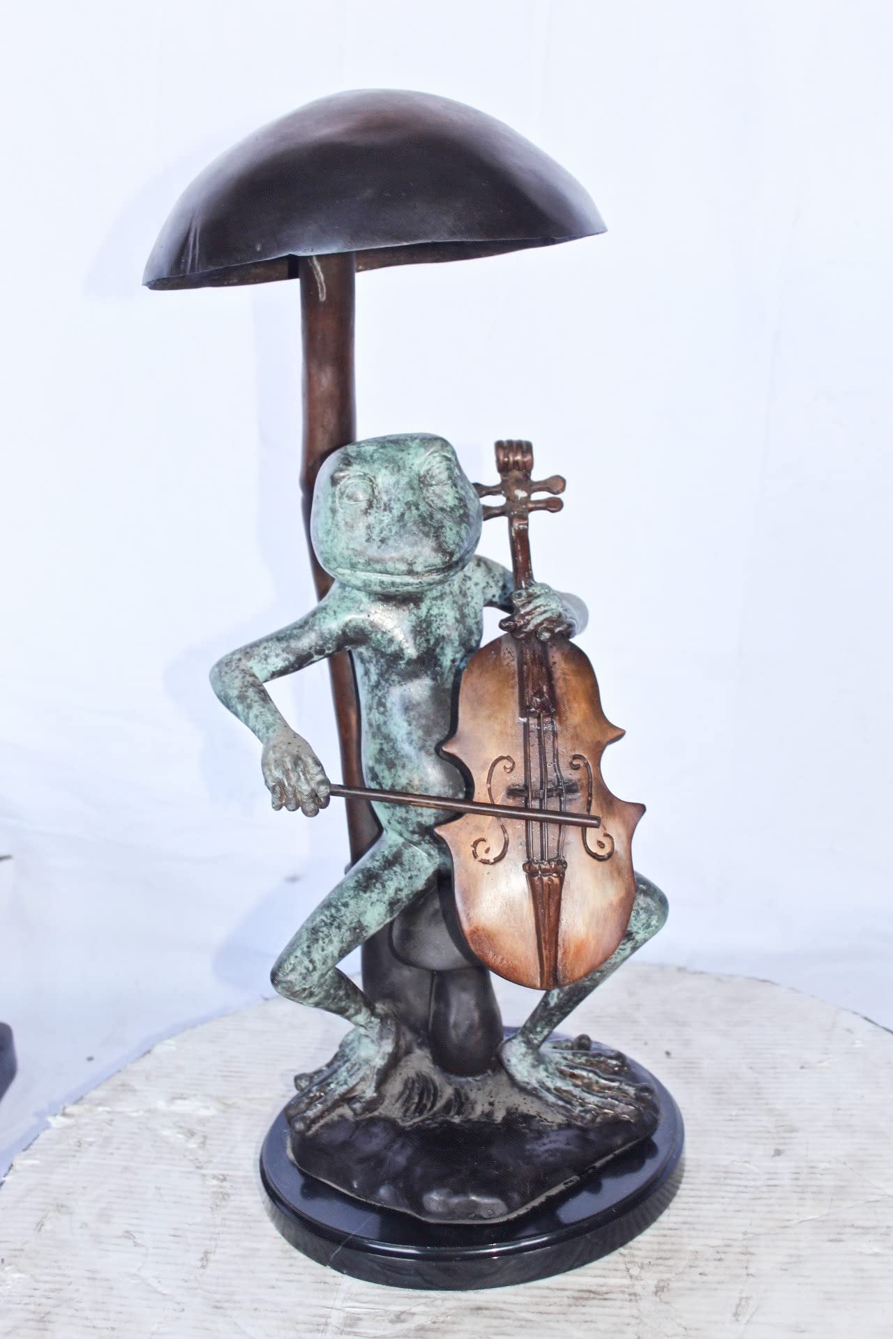 Frog playing cello under mushroom bronze statue - Size: 10"L x 10"W x 24"H.
