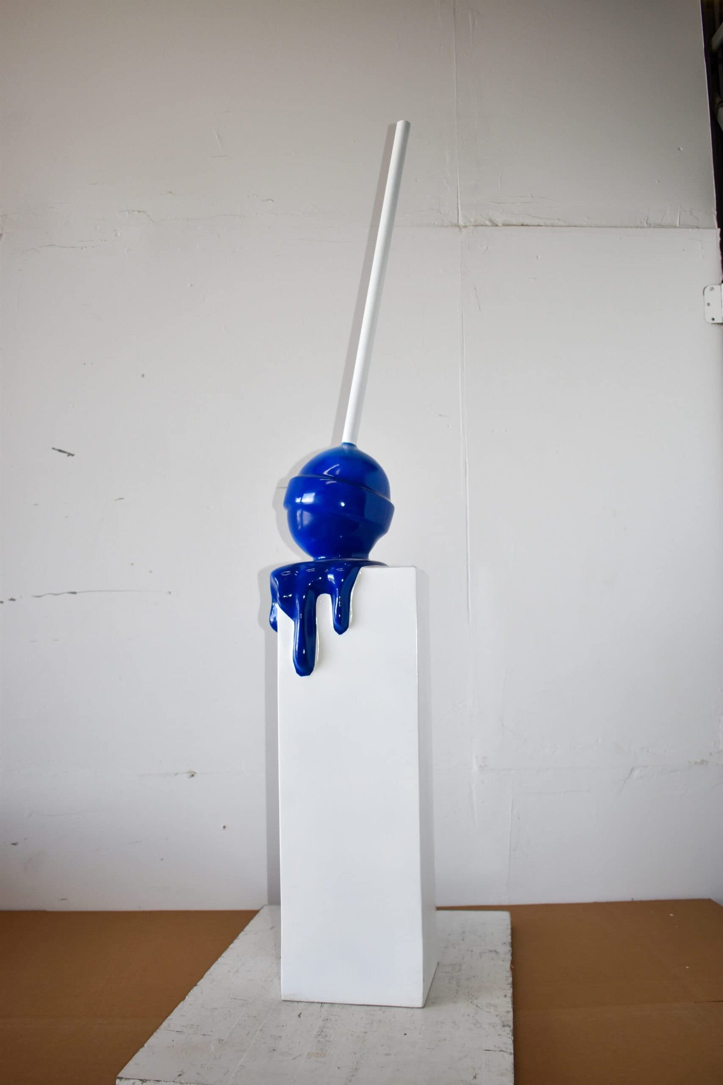 Blue Lollipop Mounted on A White Pedestal Resin Statue Size: 10" x 10" x 59"H