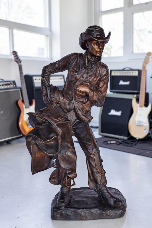 Cowboy Holding His Saddle Bronze Statue - Size: 20"L x 14"W x 35"H.