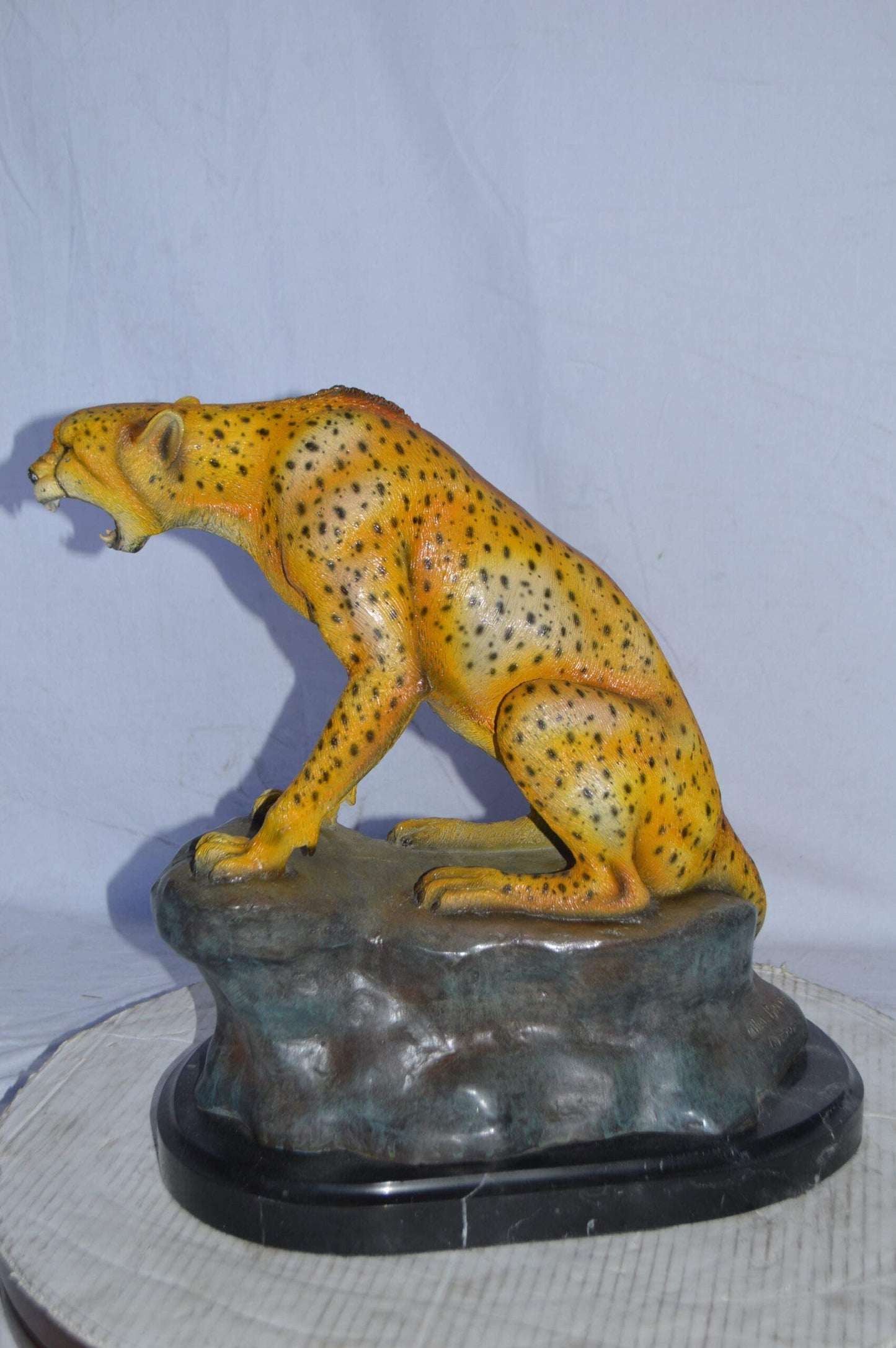 Cheetah sitting on a rock growling bronze statue - Size: 18"L x 12"W x 18"H.