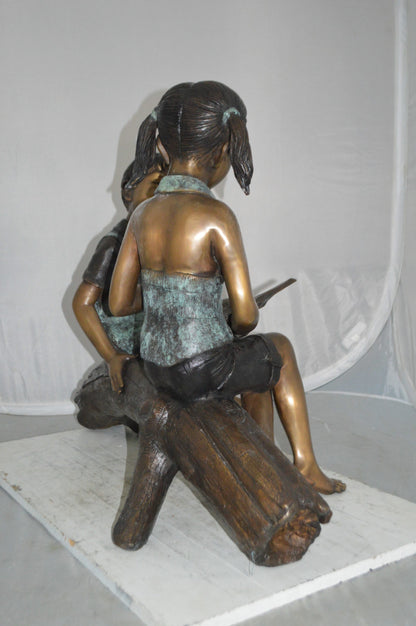 Boy and Girl on a tree log reading Bronze Statue -  Size: 37"L x 14"W x 27"H.