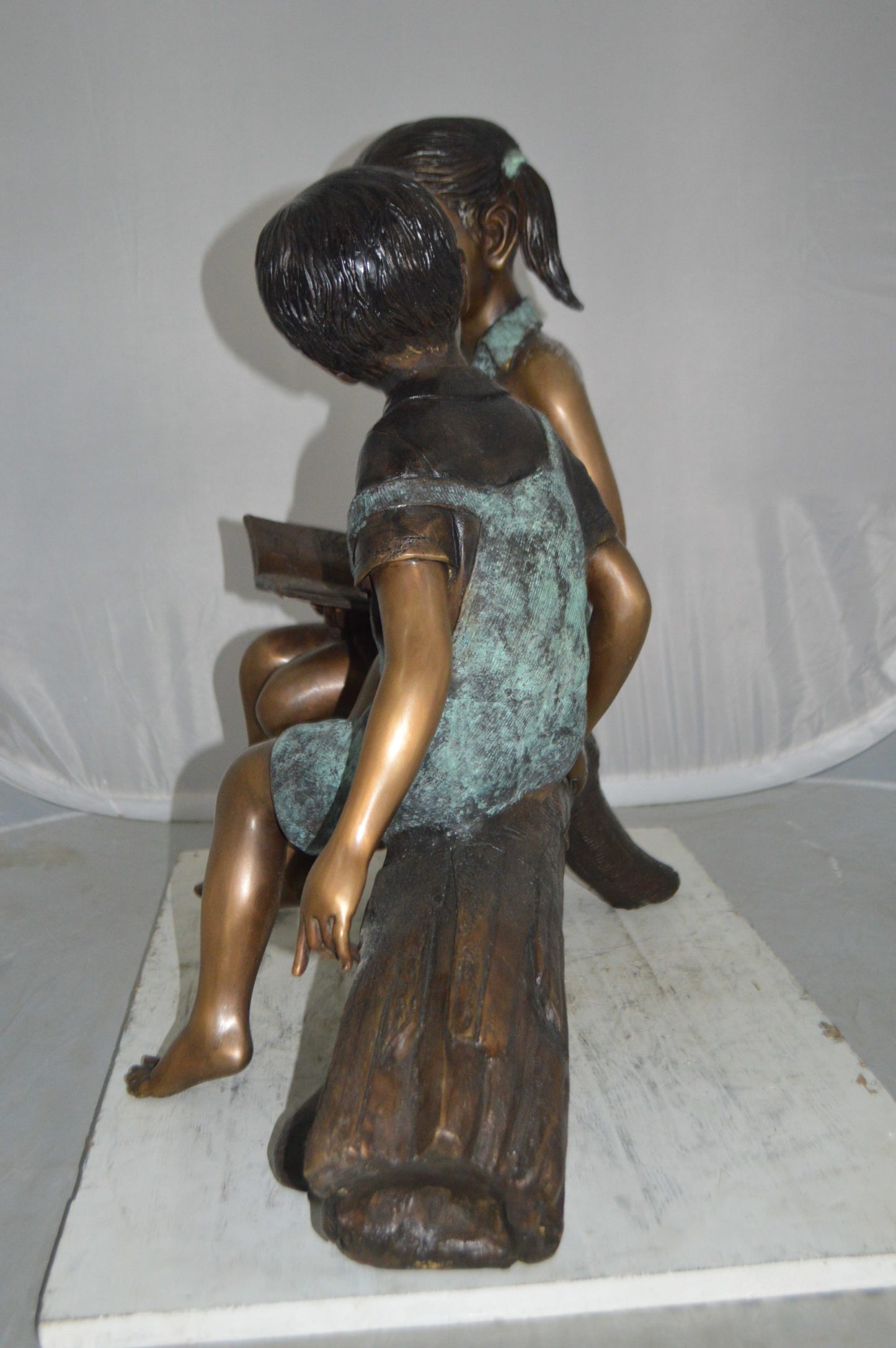 Boy and Girl on a tree log reading Bronze Statue -  Size: 37"L x 14"W x 27"H.
