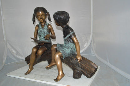 Boy and Girl on a tree log reading Bronze Statue -  Size: 37"L x 14"W x 27"H.