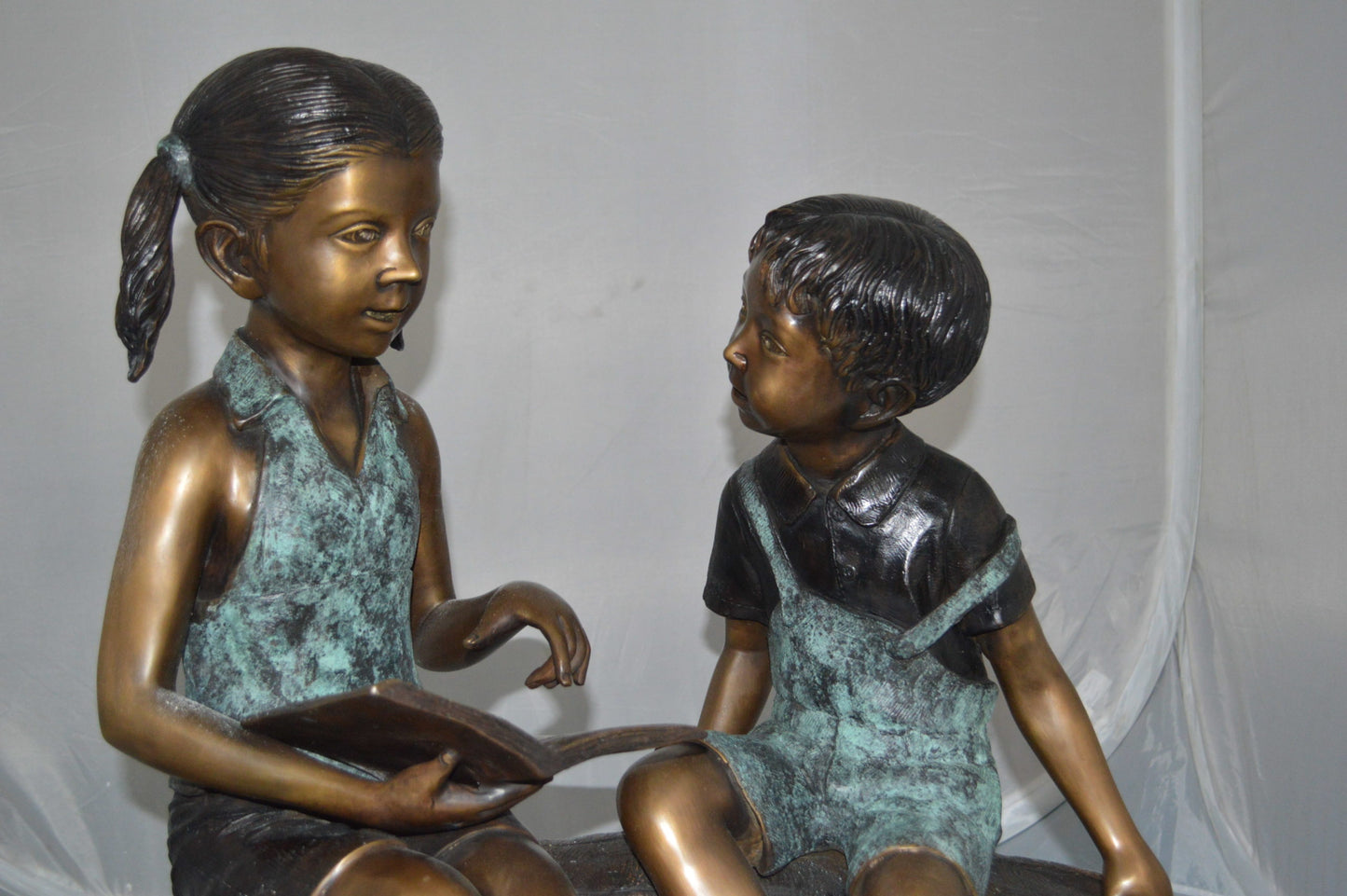 Boy and Girl on a tree log reading Bronze Statue -  Size: 37"L x 14"W x 27"H.