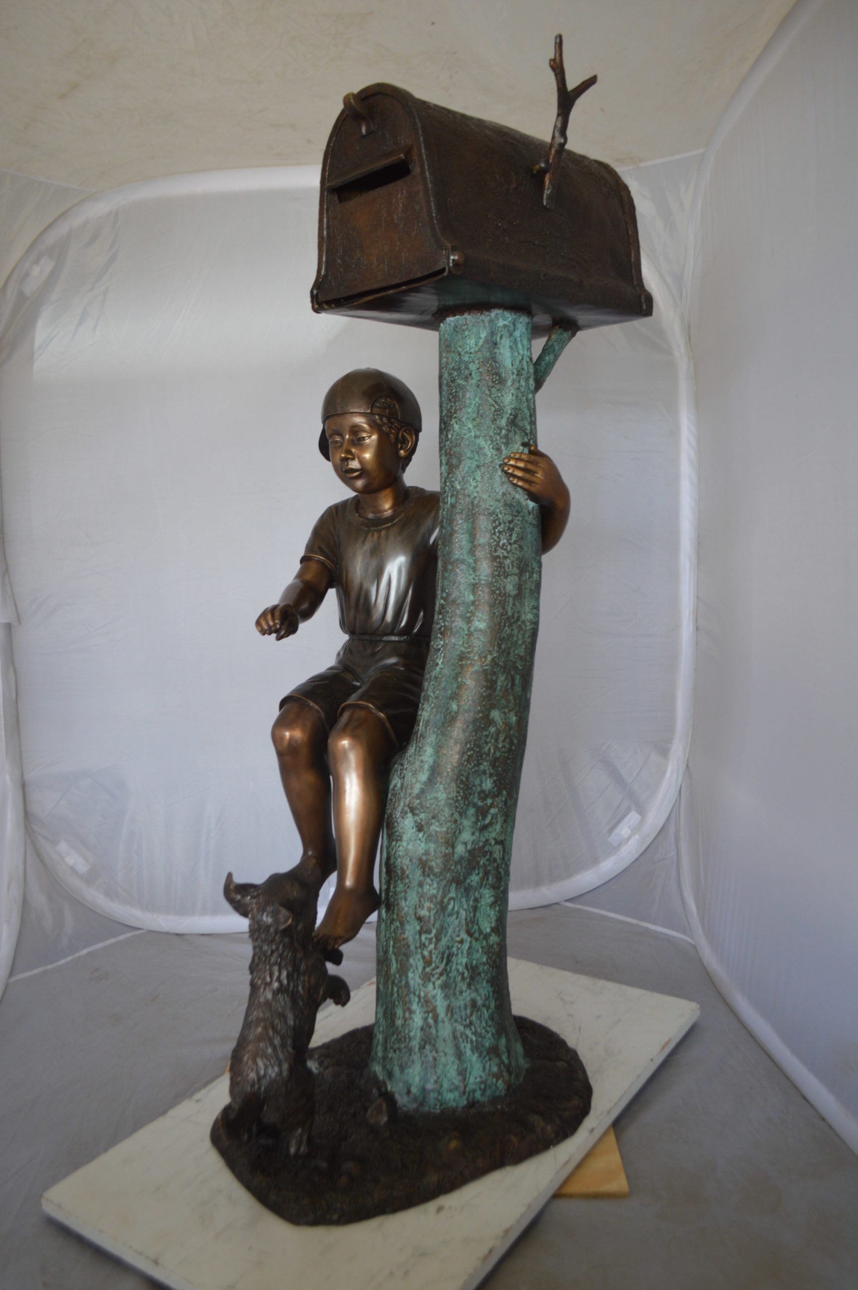 Boy Sitting on a Tree with Mailbox Bronze Statue -  Size: 22"L x 23"W x 49"H. 