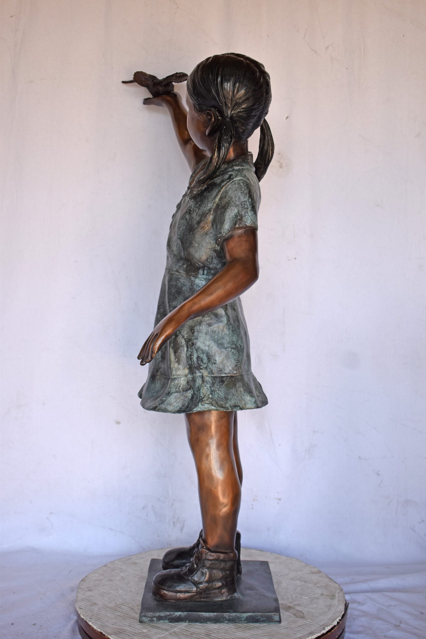 Young Girl Holding a Bird Outside at The Park - Size: 21"L x 11"W x 49"H.