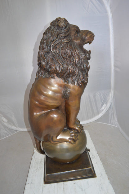 Pair of lions standing on balls, bronze statues -  Size: 14"L x 16"W x 38"H. 