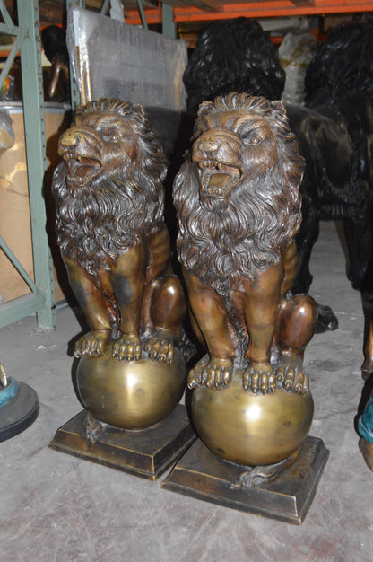 Pair of lions standing on balls, bronze statues -  Size: 14"L x 16"W x 38"H. 