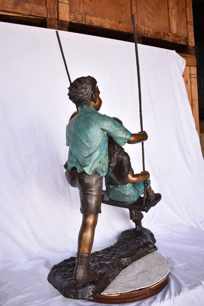 Boy and Girl Playing on a Swing bronze Statue - Size: 39"L x 17"W x 53"H.