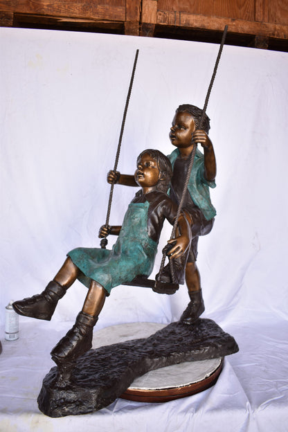 Boy and Girl Playing on a Swing bronze Statue - Size: 39"L x 17"W x 53"H.