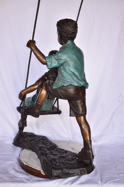 Boy and Girl Playing on a Swing bronze Statue - Size: 39"L x 17"W x 53"H.