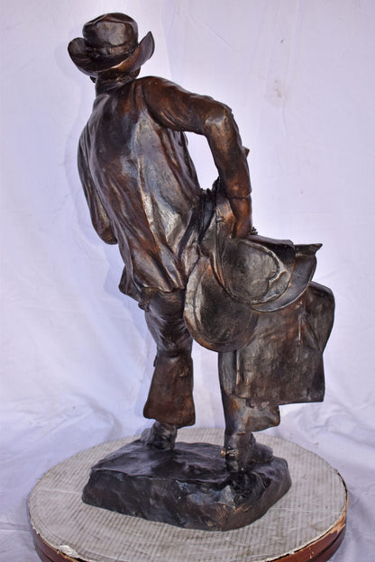 Cowboy Holding His Saddle Bronze Statue - Size: 20"L x 14"W x 35"H.