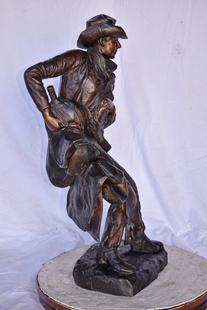 Cowboy Holding His Saddle Bronze Statue - Size: 20"L x 14"W x 35"H.