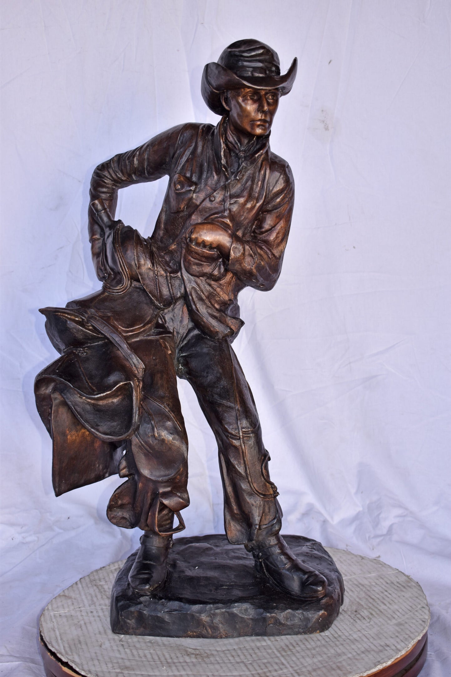 Cowboy Holding His Saddle Bronze Statue - Size: 20"L x 14"W x 35"H.