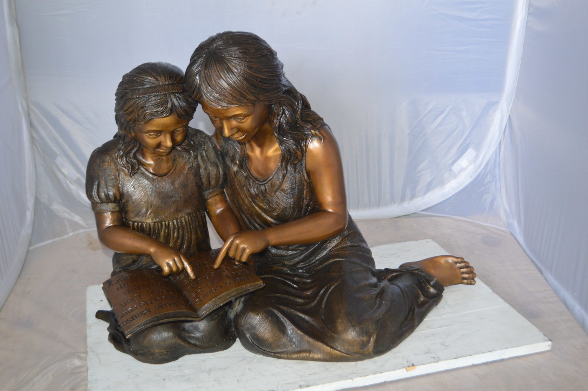 Two Girls Reading a Book Bronze Statue -  Size: 33"L x 21"W x 23"H. 