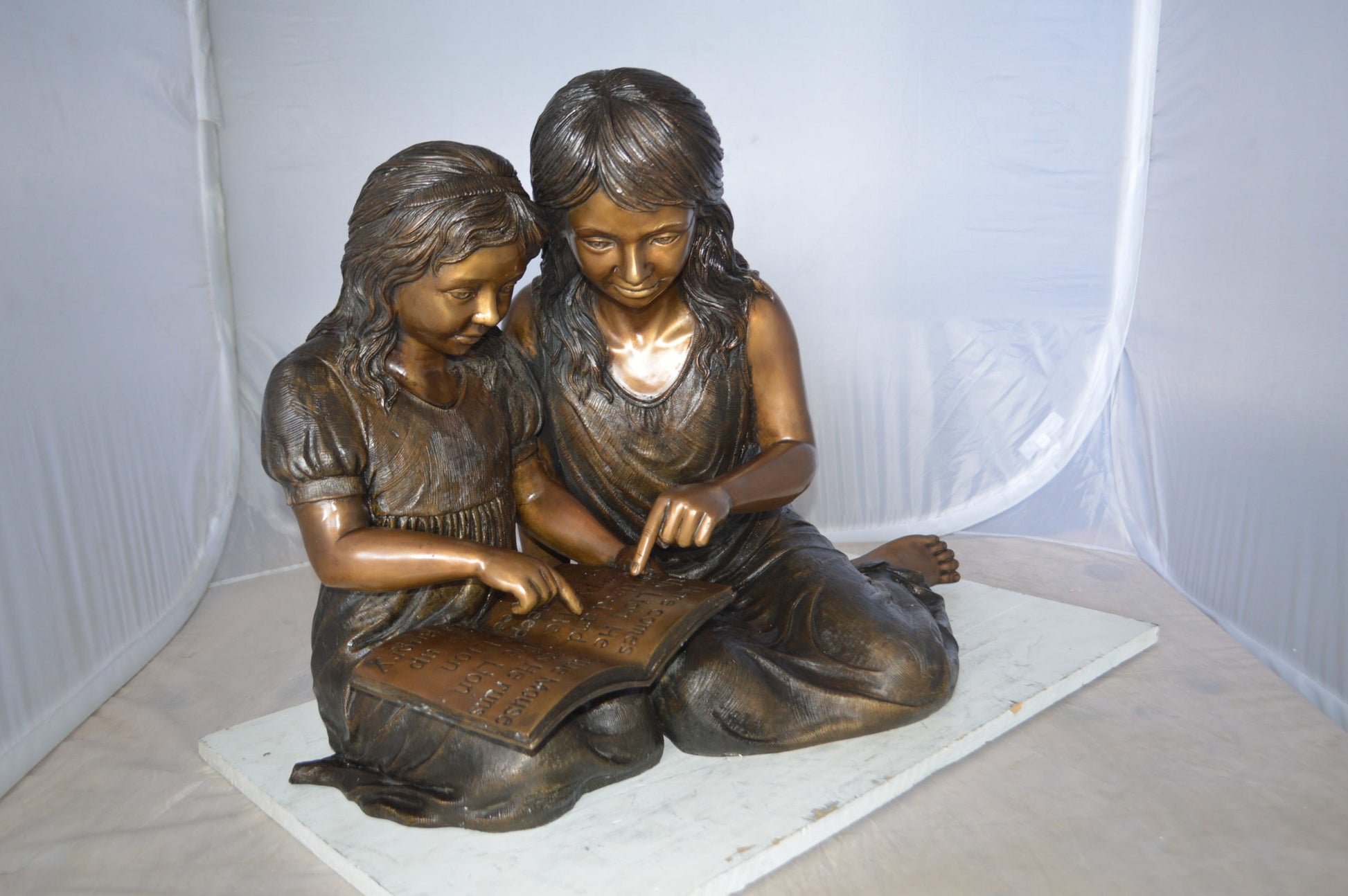 Two Girls Reading a Book Bronze Statue -  Size: 33"L x 21"W x 23"H. 