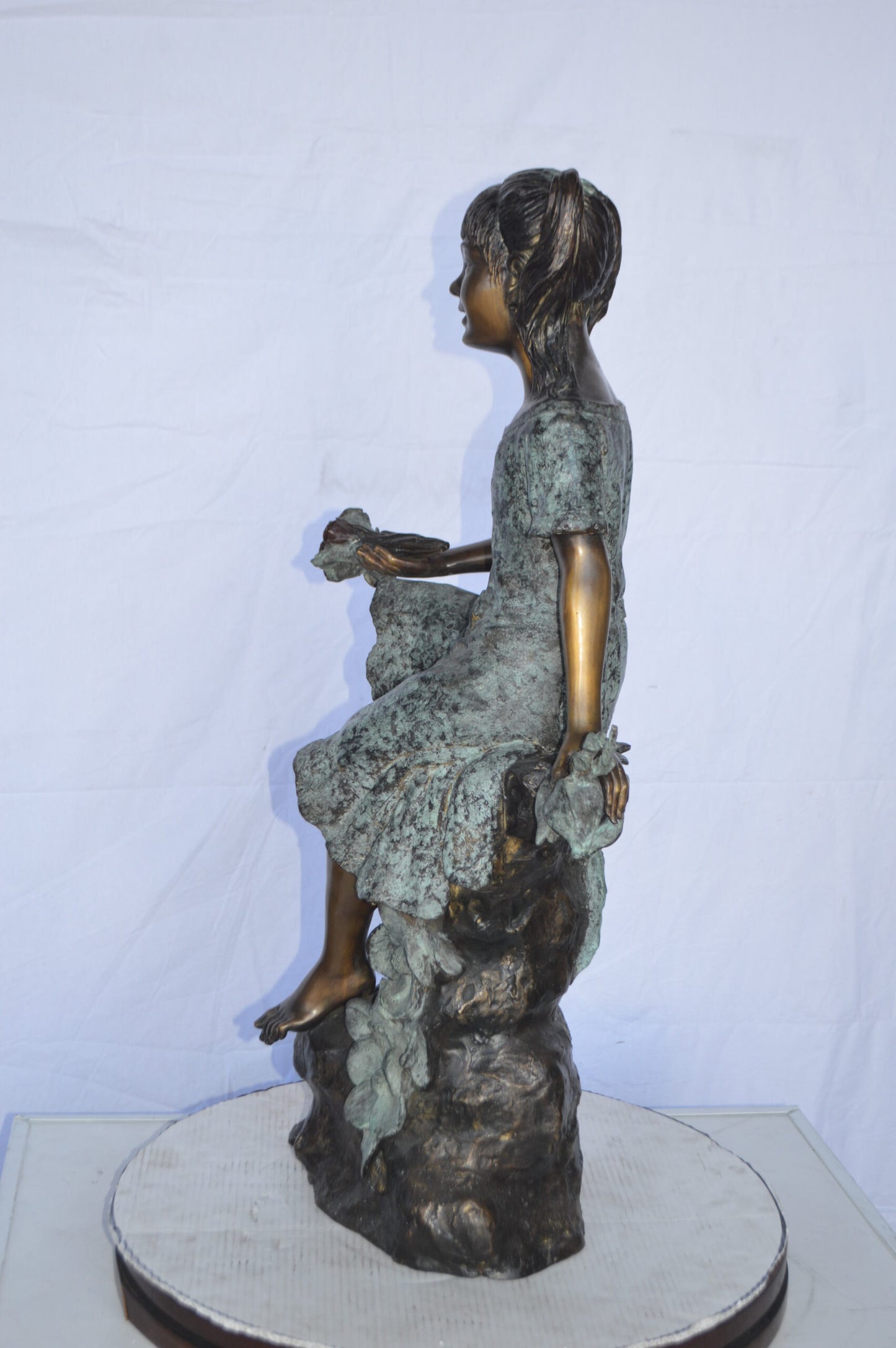 Girl on Tree  Trunk Holding Flowers Bronze Statue -  Size: 26"L x 11"W x 36"H.