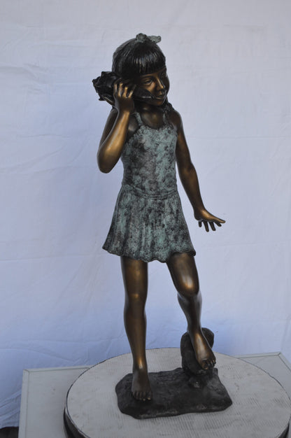 Standing Girl Listening to a Shell Bronze Statue -  Size: 16"L x 12"W x 37"H.