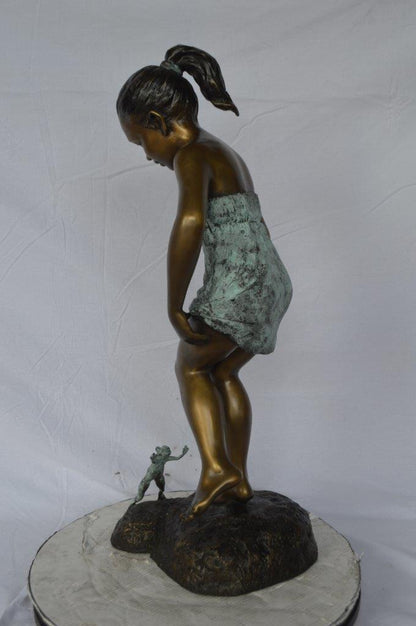 Girl looking at a frog bronze statue -  Size: 16"L x 13"W x 36"H.