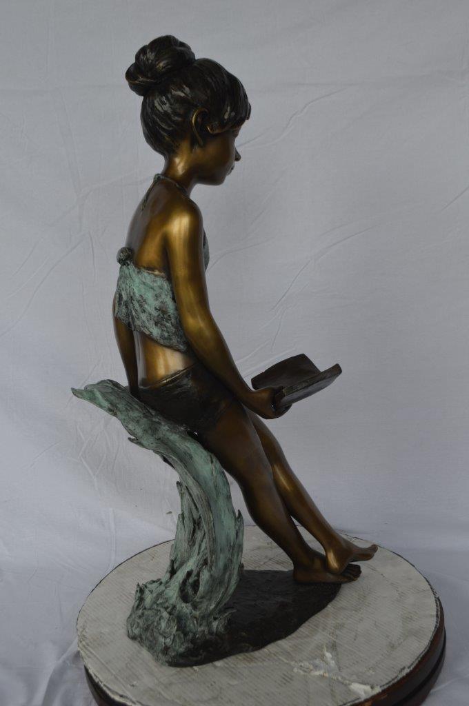 Girl sitting and reading a book bronze statue -  Size: 19"L x 15"W x 36"H.