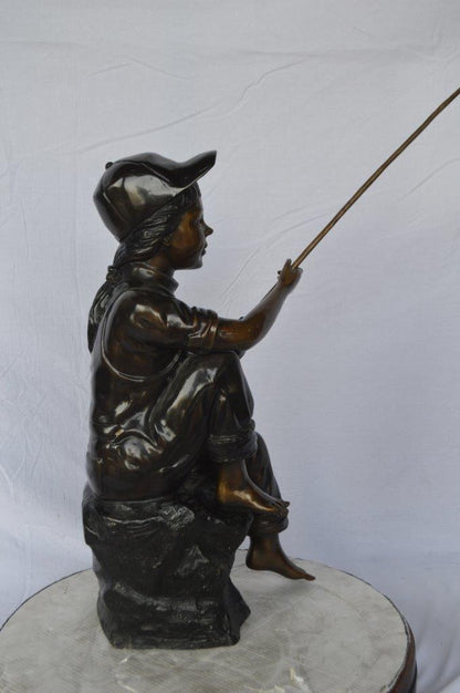 Young Boy sitting on a rock fishing bronze statue -  Size: 31"L x 9"W x 33"H.
