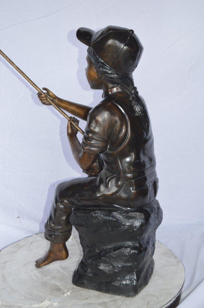Young Boy sitting on a rock fishing bronze statue -  Size: 31"L x 9"W x 33"H.