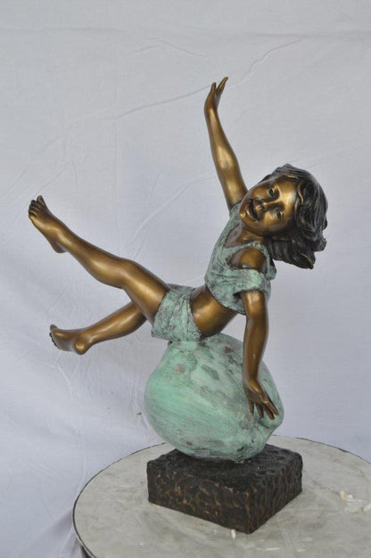 Girl having fun on apple bronze statue -  Size: 22"L x 9"W x 31"H.