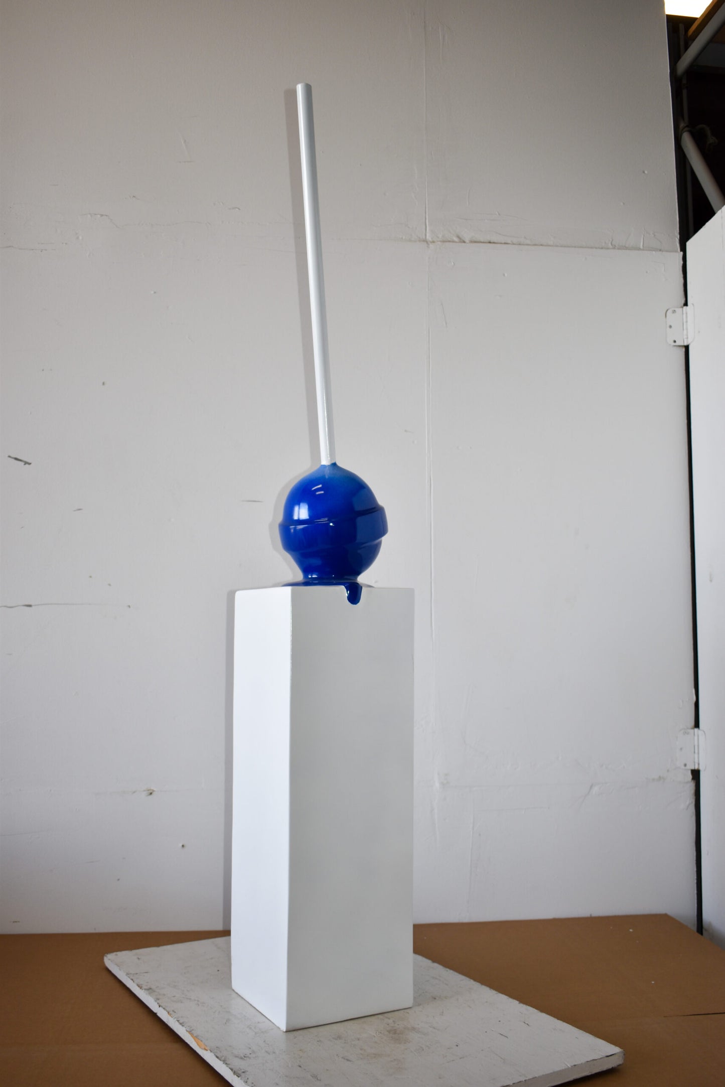 Blue Lollipop Mounted on A White Pedestal Resin Statue Size: 10" x 10" x 59"H
