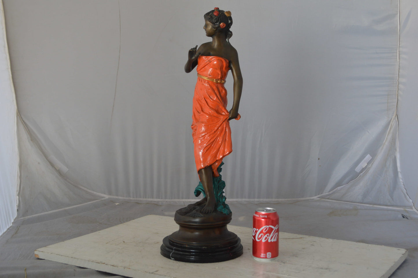 Young lady in orange bronze statue - Size: 7"L x 26"W x 25"H.