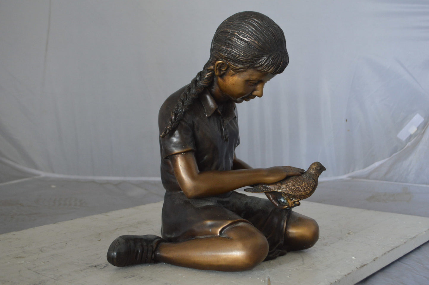 Young seated girl with bird bronze statue - Size: 12"L x 9"W x 14"H.