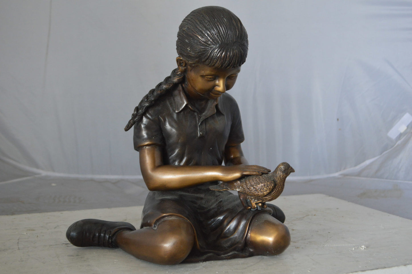 Young seated girl with bird bronze statue - Size: 12"L x 9"W x 14"H.