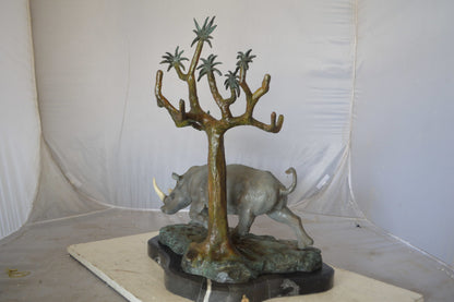 Rhino Relaxed under a tree bronze statue - Size: 22"L x 15"W x 25"H.