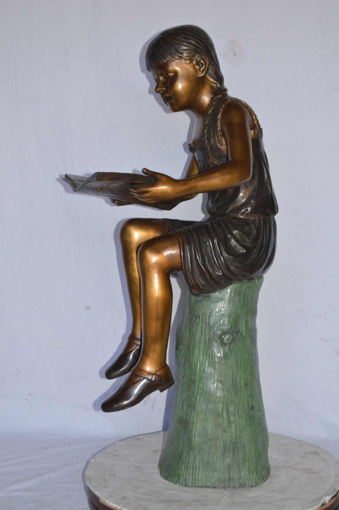 Girl Sitting on a Tree Stump, Reading Bronze Statue - Size: 15"L x 20"W x 22"H.