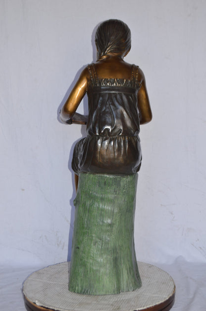 Girl Sitting on a Tree Stump, Reading Bronze Statue - Size: 15"L x 20"W x 22"H.