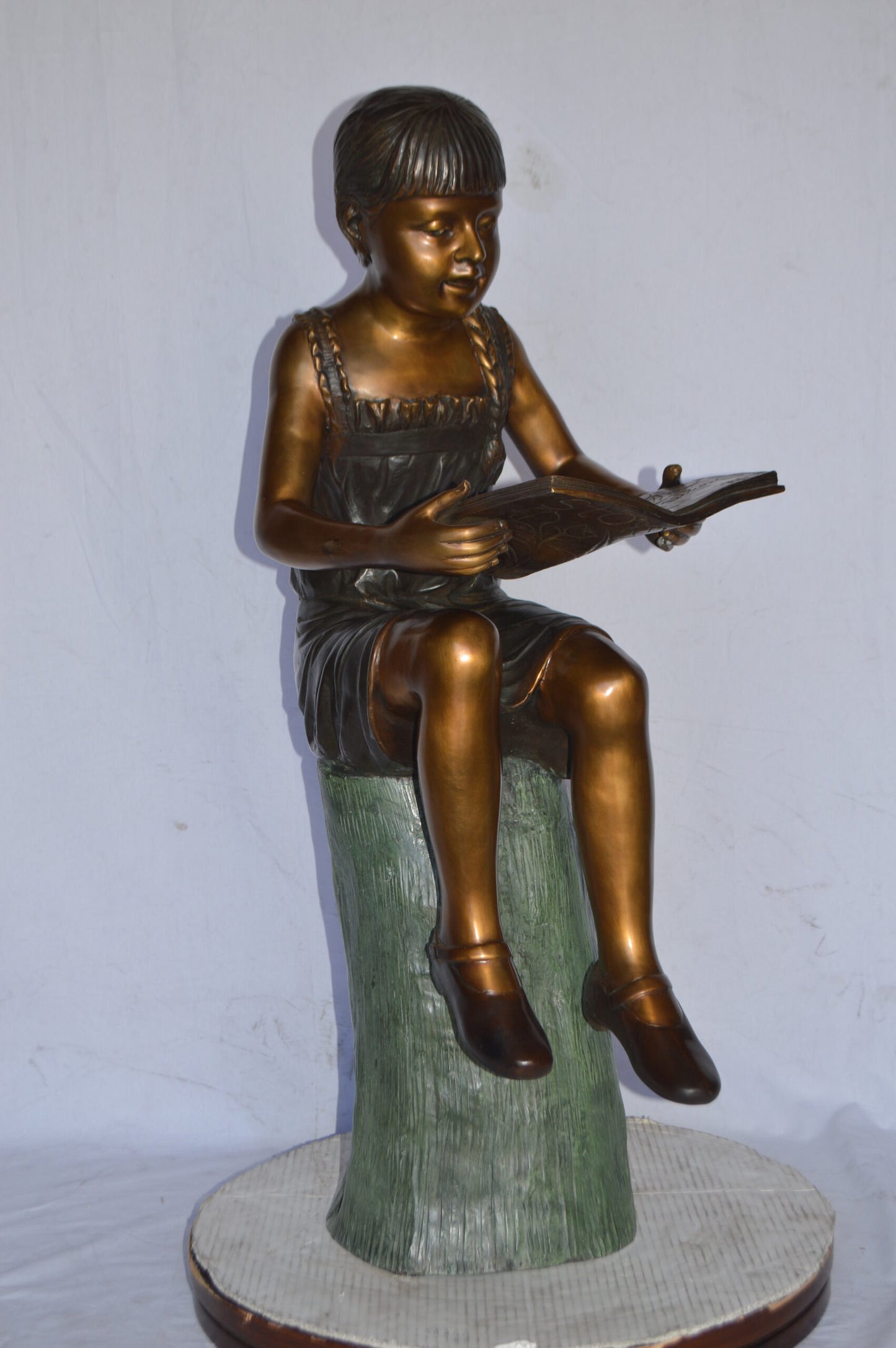 Girl Sitting on a Tree Stump, Reading Bronze Statue - Size: 15"L x 20"W x 22"H.