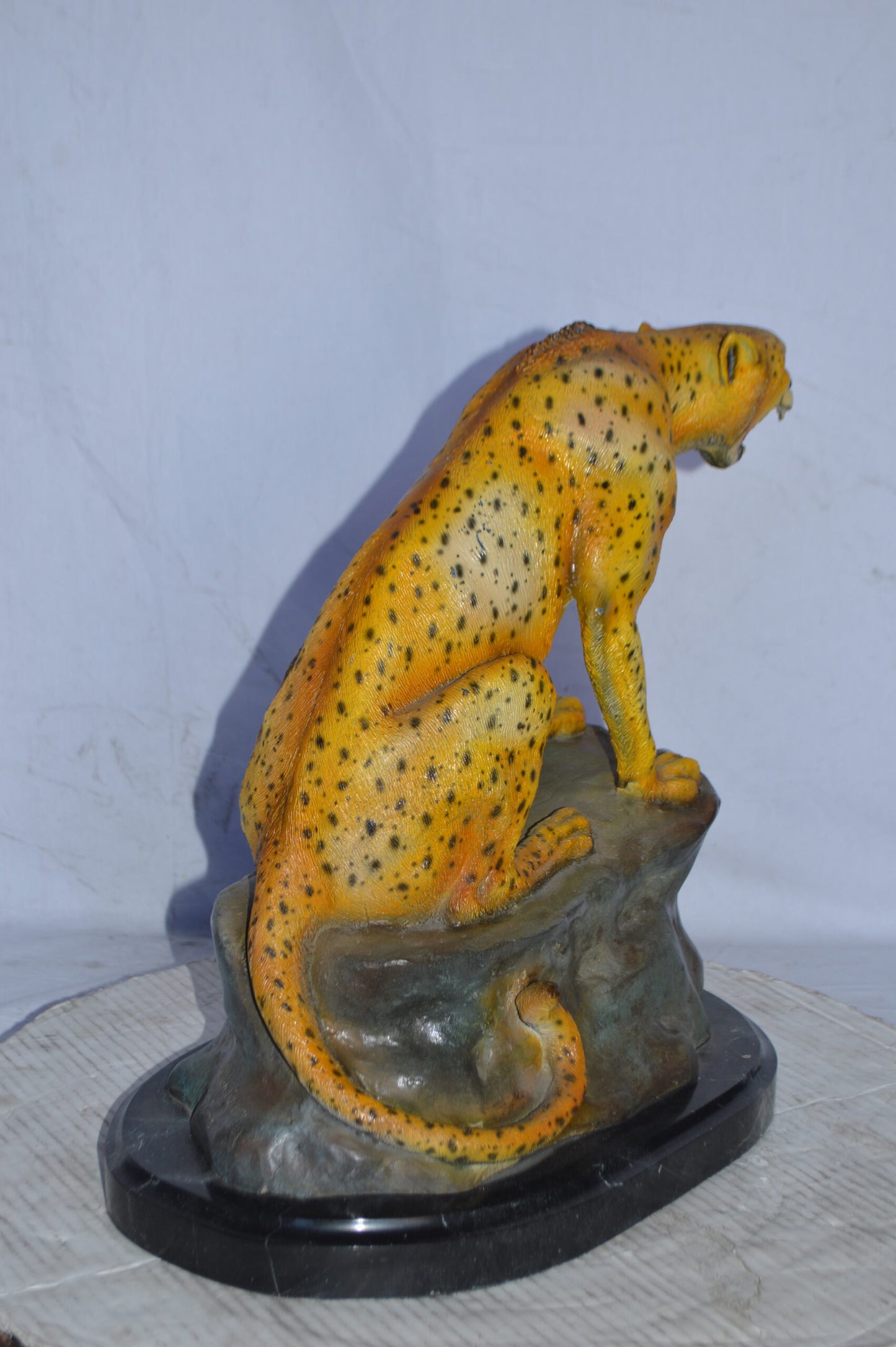 Cheetah sitting on a rock growling bronze statue - Size: 18"L x 12"W x 18"H.