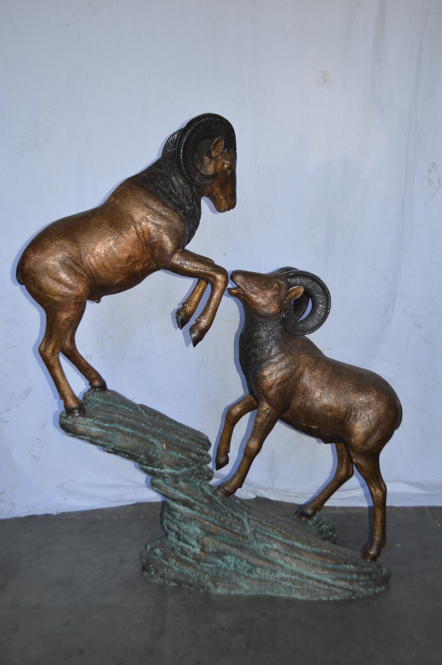Two Life Size Rams on a rock Bronze Statue - Size: 49"L x 20"W x 64"H.