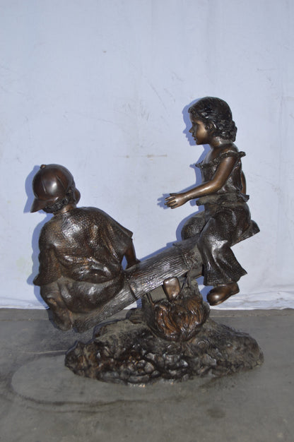A Boy and a Girl Playing Seesaw Bronze Statue - Size: 17"L x 33"W x 36"H.