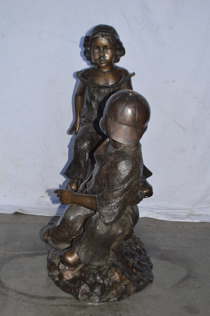 A Boy and a Girl Playing Seesaw Bronze Statue - Size: 17"L x 33"W x 36"H.