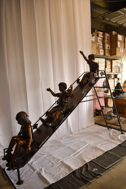 Lifsize Three kids playing on a slide bronze sculpture 114" x 18" x 83"H