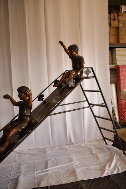 Lifsize Three kids playing on a slide bronze sculpture 114" x 18" x 83"H