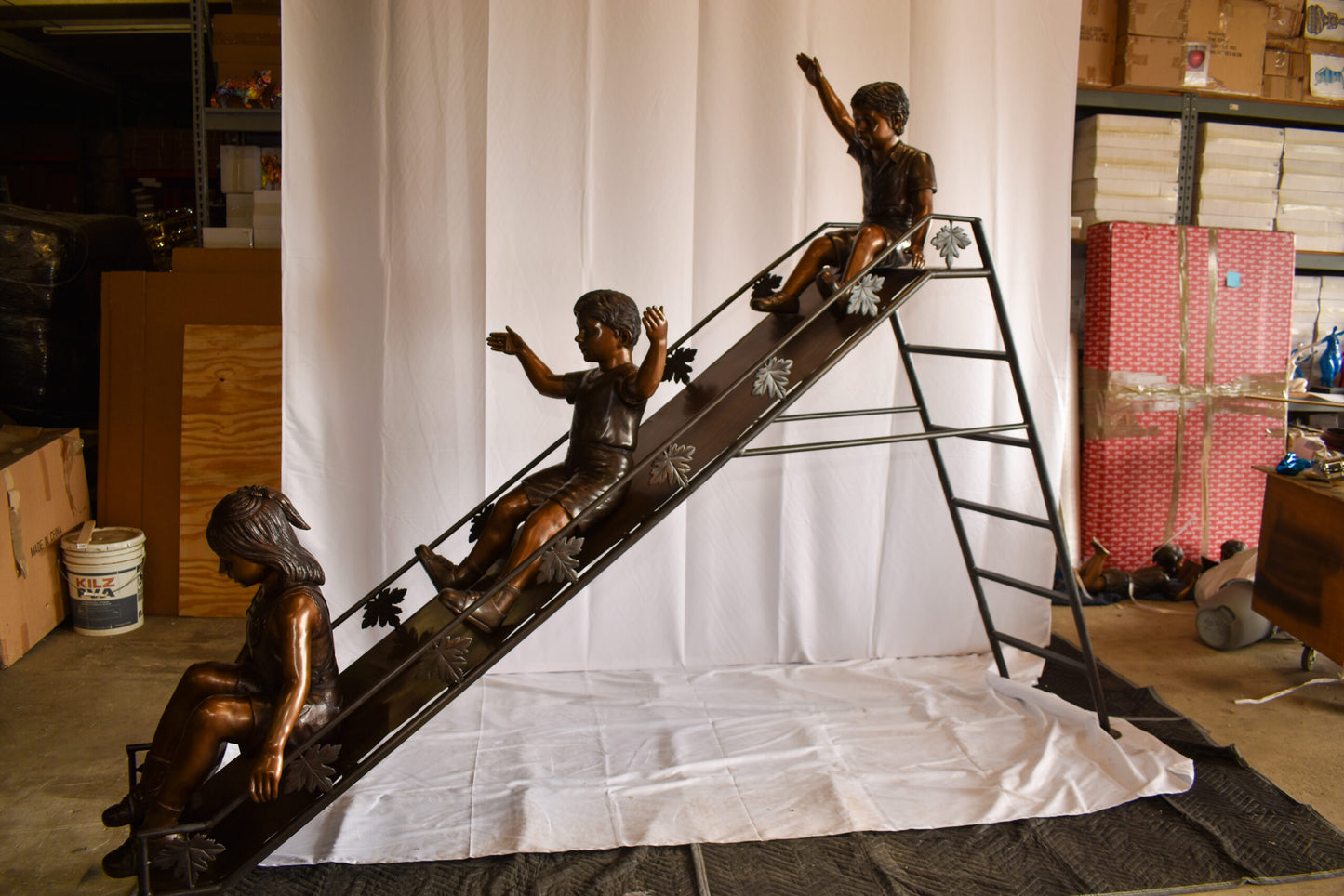 Lifsize Three kids playing on a slide bronze sculpture 114" x 18" x 83"H