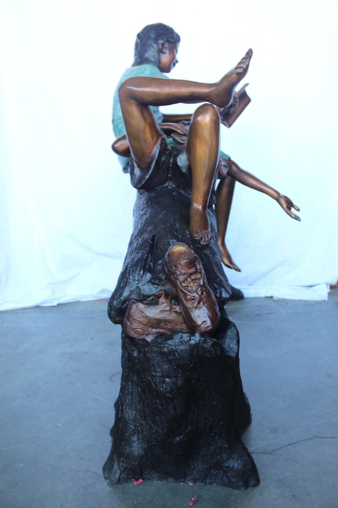 Boy and girl reading on arched tree bronze statue  -  Size: 70"L x 29"W x 56"H.