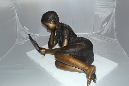 Girl laying reading a book Bronze Statue -  Size: 36"L x 17"W x 18"H. 