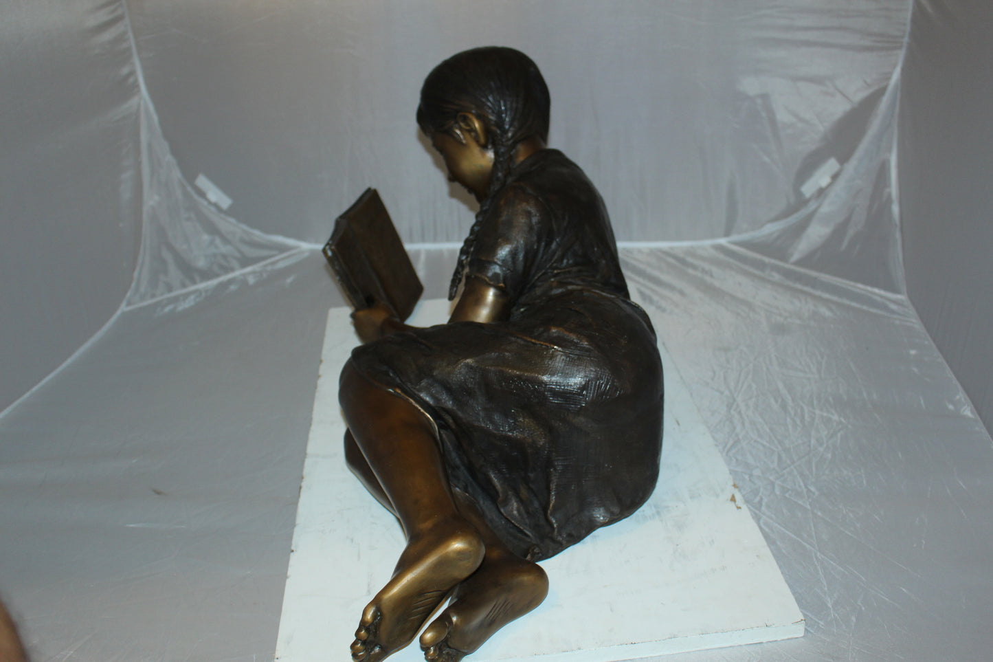 Girl laying reading a book Bronze Statue -  Size: 36"L x 17"W x 18"H. 