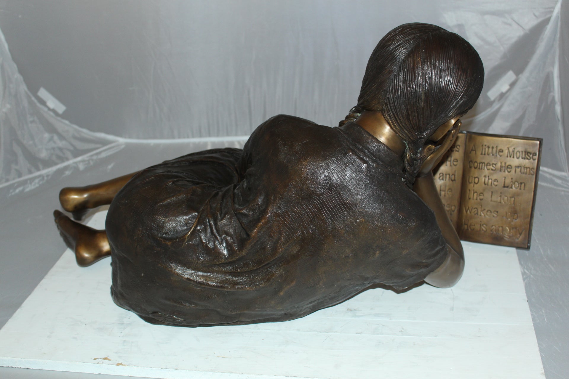 Girl laying reading a book Bronze Statue -  Size: 36"L x 17"W x 18"H. 