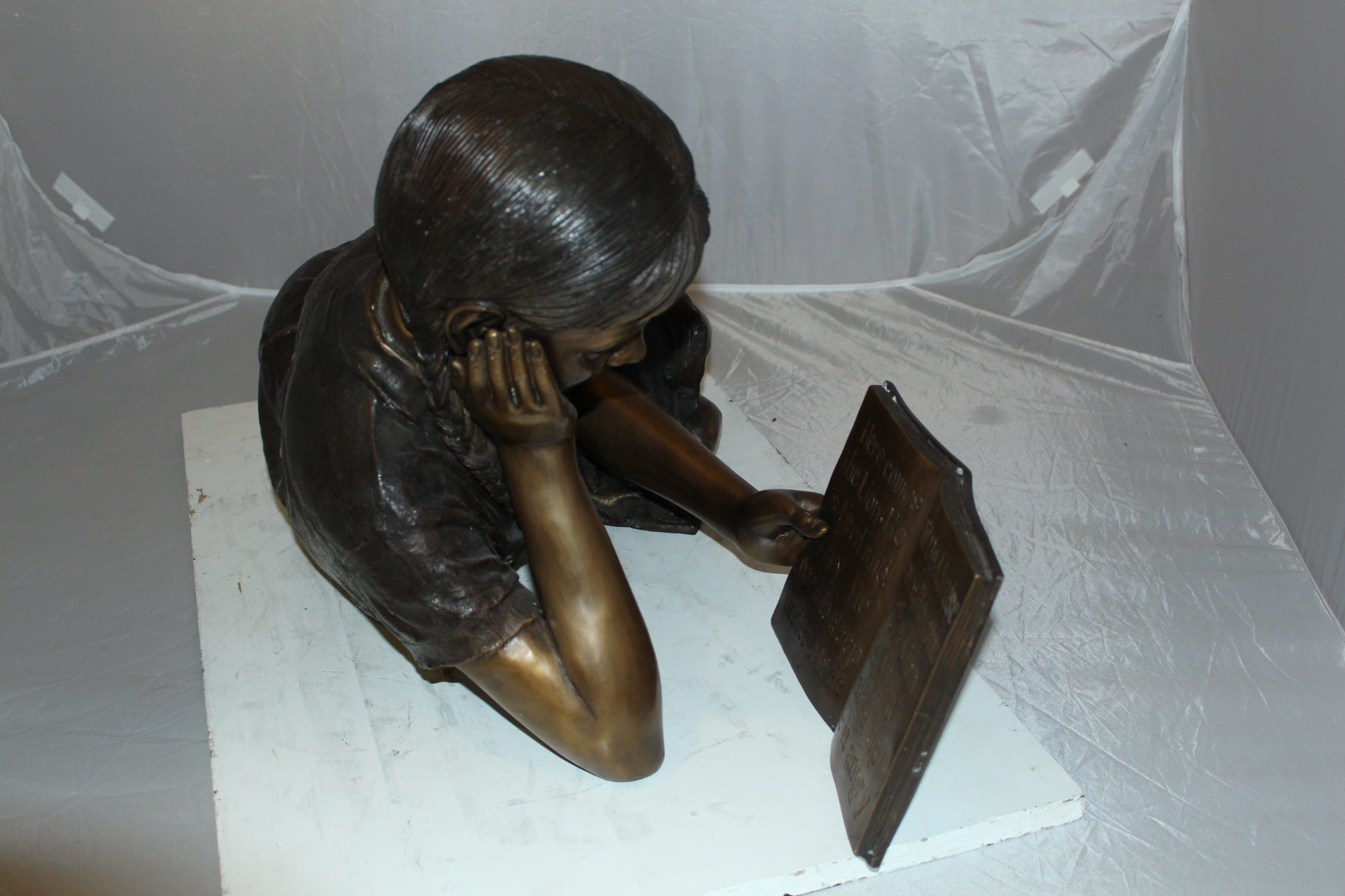 Girl laying reading a book Bronze Statue -  Size: 36"L x 17"W x 18"H. 