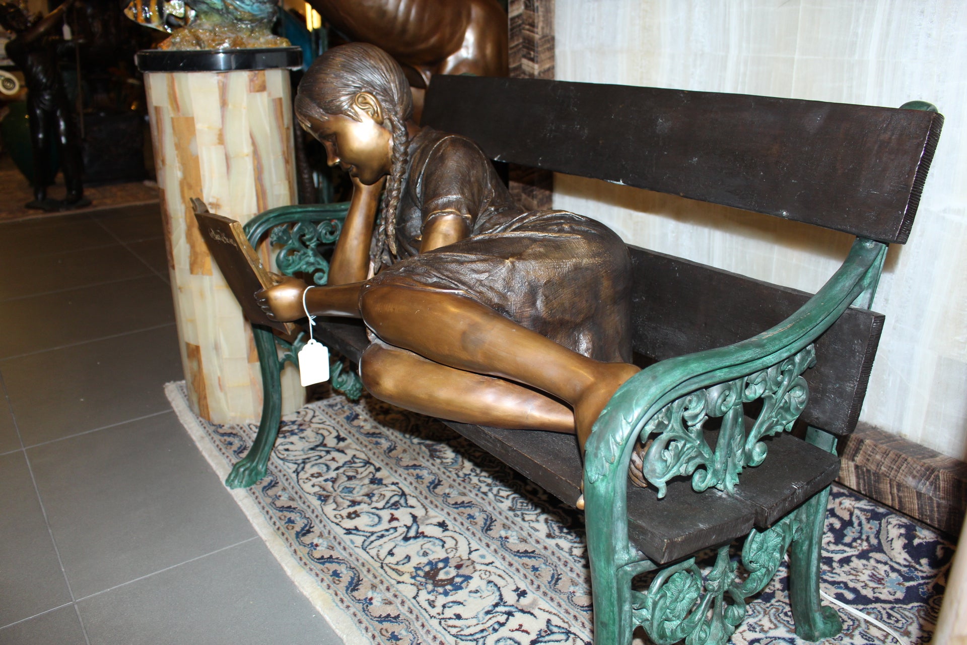 Girl laying on a bench reading a book Bronze Statue -  Size: 27"L x 39"W x 32"H