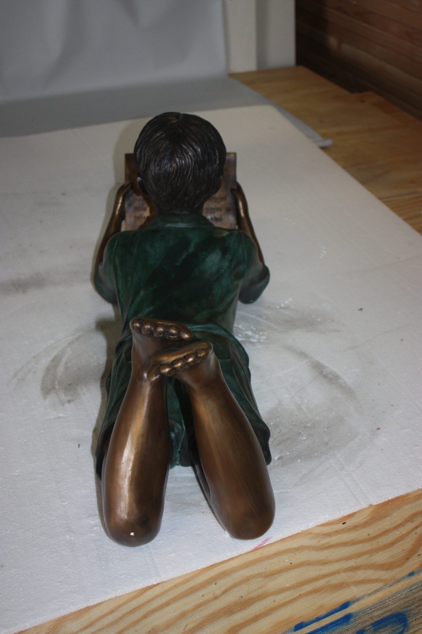 boy laying reading book bronze Statue -  Size: 24"L x 10"W x 11"H. 