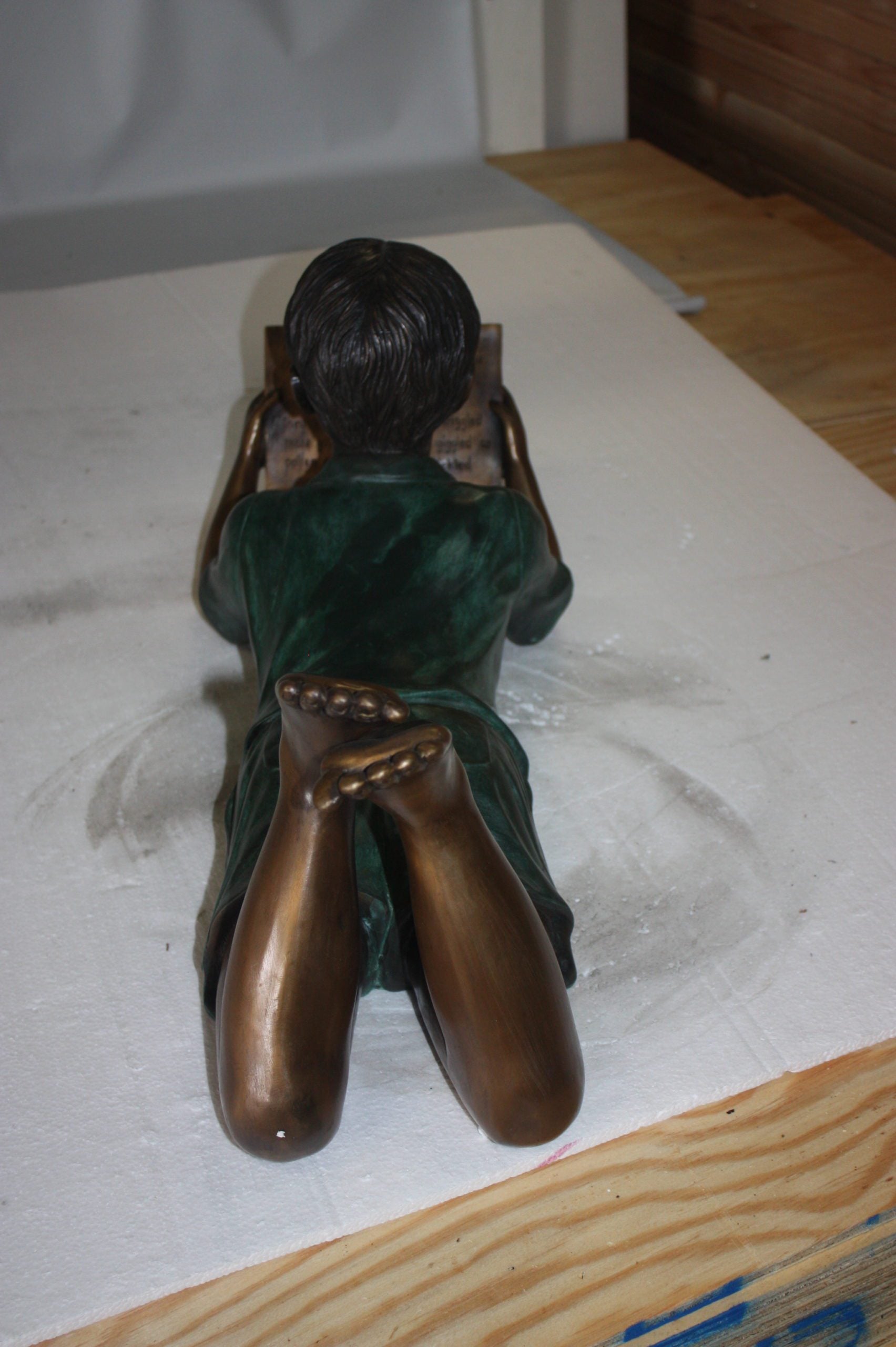 boy laying reading book bronze Statue -  Size: 24"L x 10"W x 11"H. 